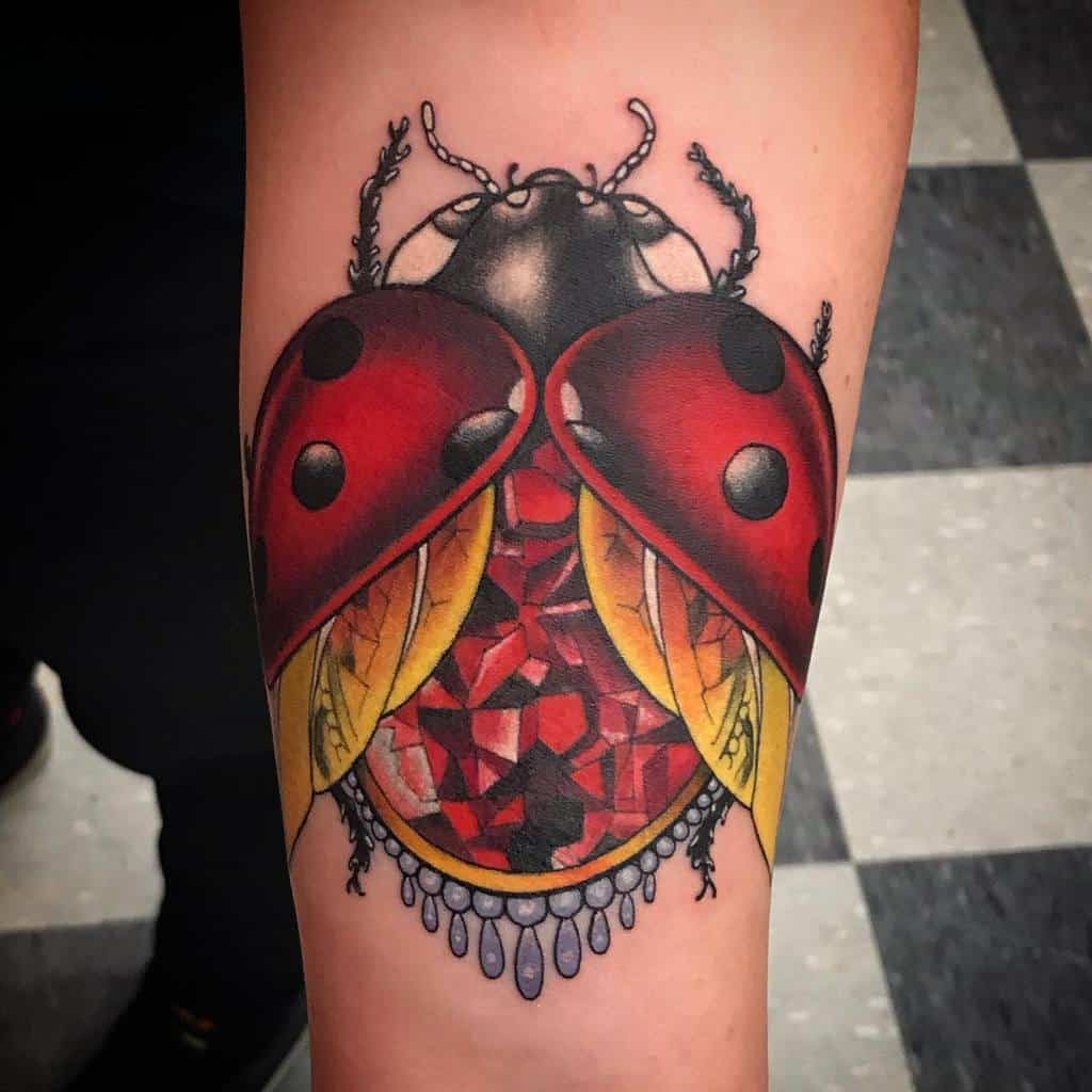 Bold ladybug tattoo with a jeweled, ruby-like body, golden wings, and intricate detailing, blending realism with a luxurious artistic touch.