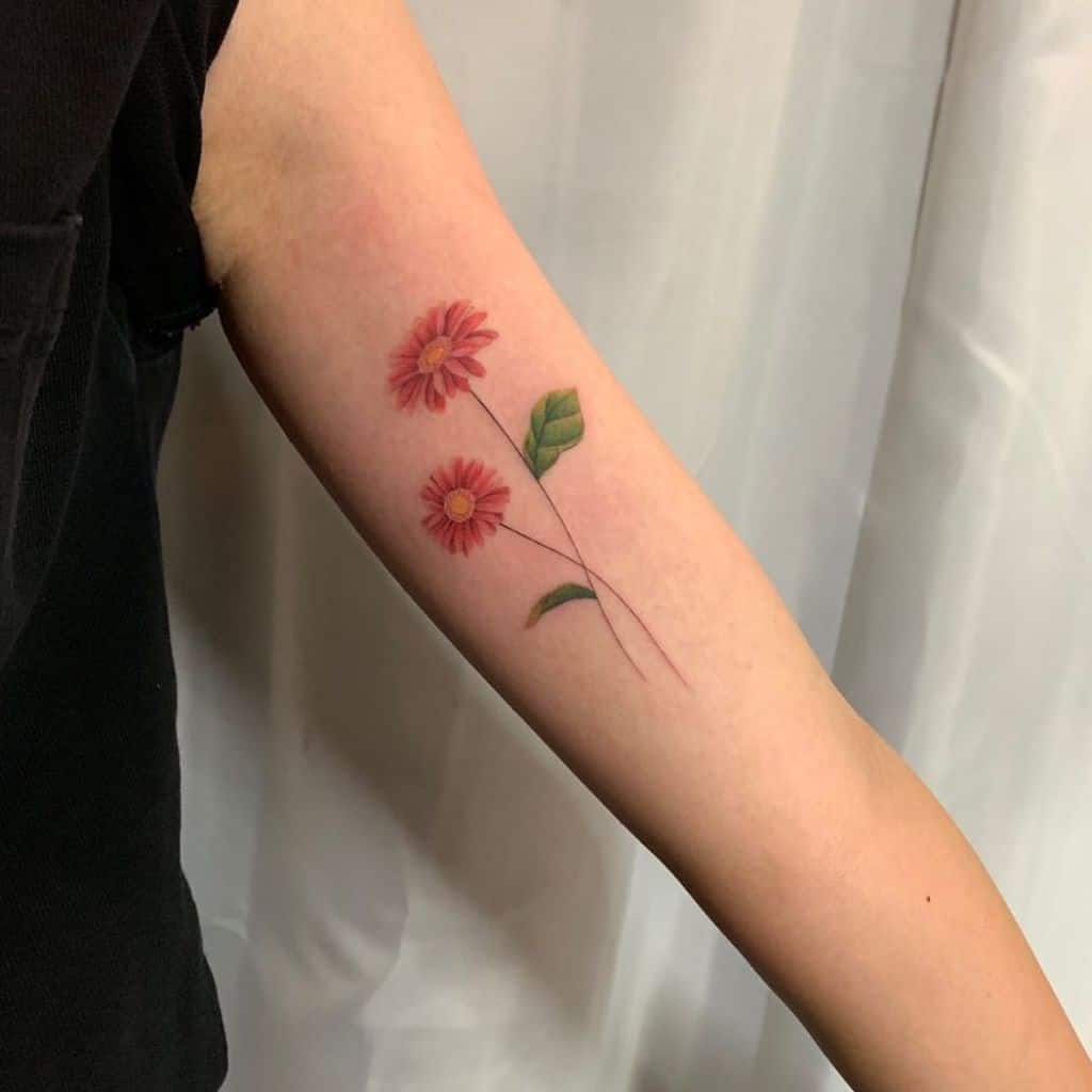 Bicep tattoo fine line color red green yellow delicate daisy