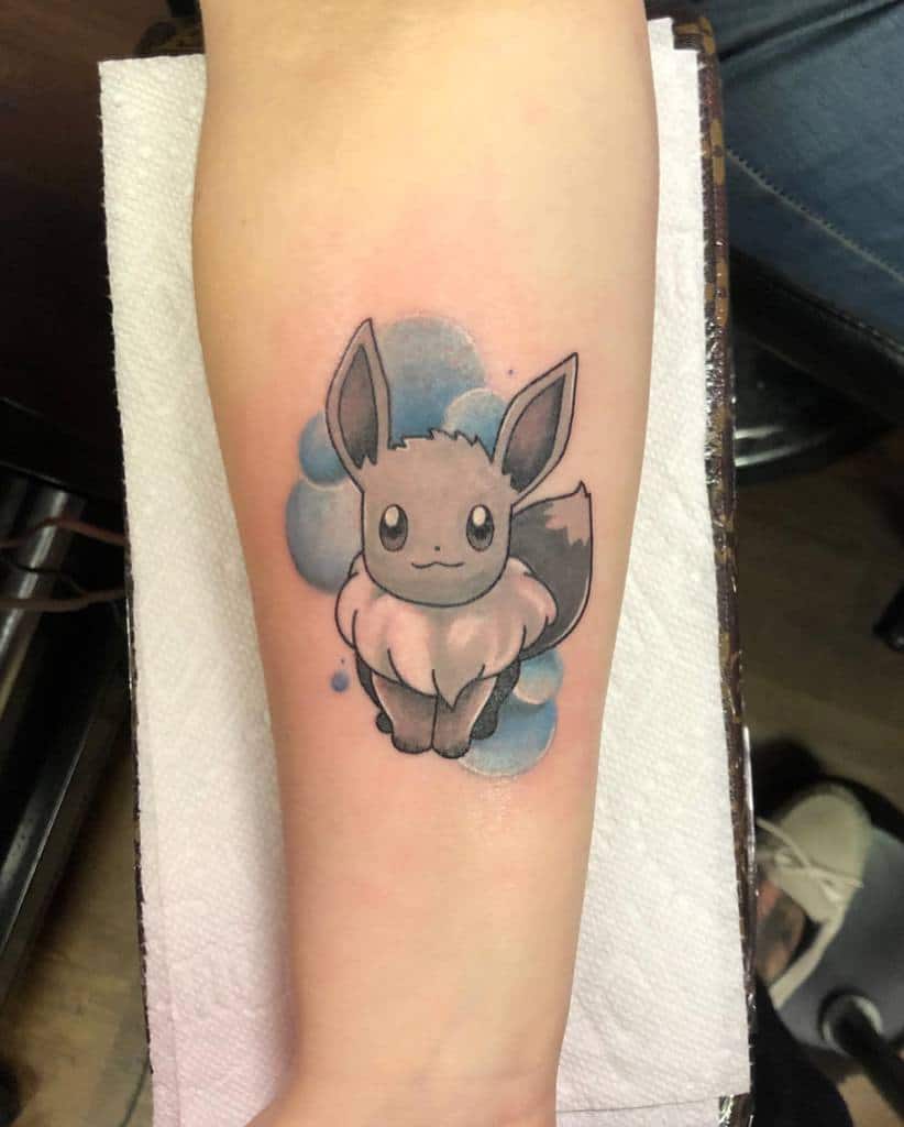 Minimalist Eevee tattoo with soft black and grey shading, accented by a dreamy blue watercolor background for a gentle effect