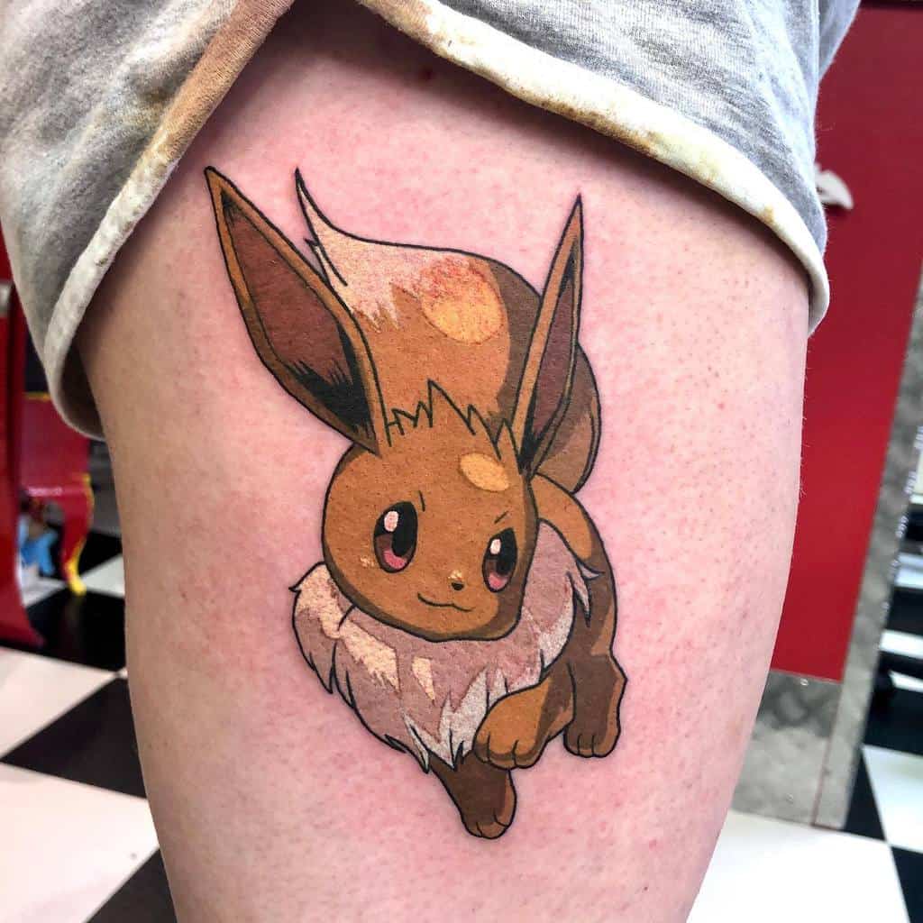 Bright Eevee tattoo on thigh with detailed fur shading, showcasing a dynamic and cheerful design