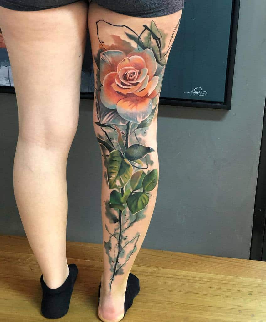 A large, detailed leg sleeve tattoo of a rose and stem
