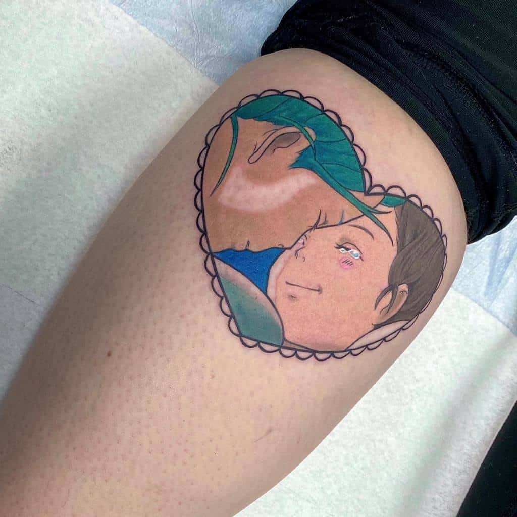 Color tattoo of Chihiro and Haku from Spirited Away in an emotional moment, framed within a heart-shaped lace border
