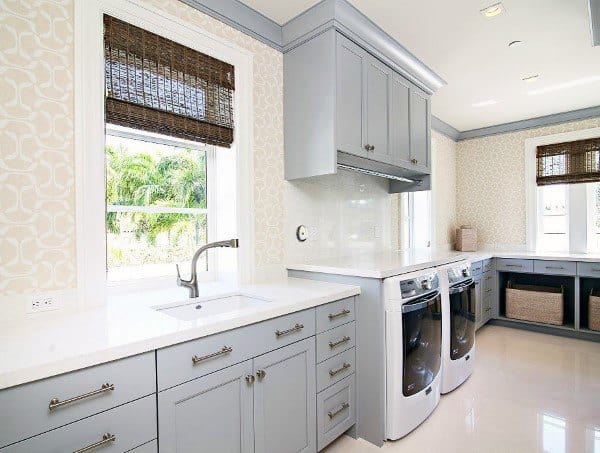 Bright laundry room with gray cabinets, modern washers, and natural light through large windows.
