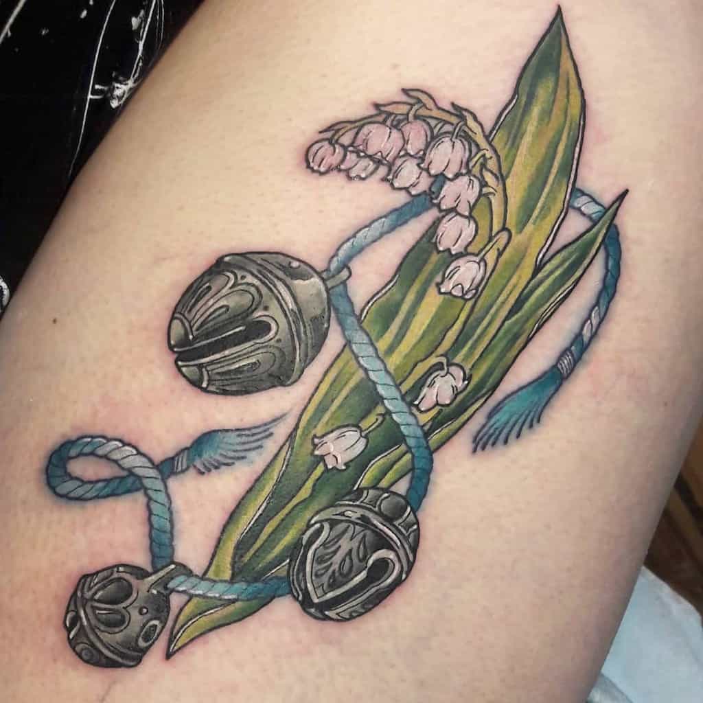 Ornate Lily of the Valley tattoo with detailed green leaves, metallic bells, and a blue rope