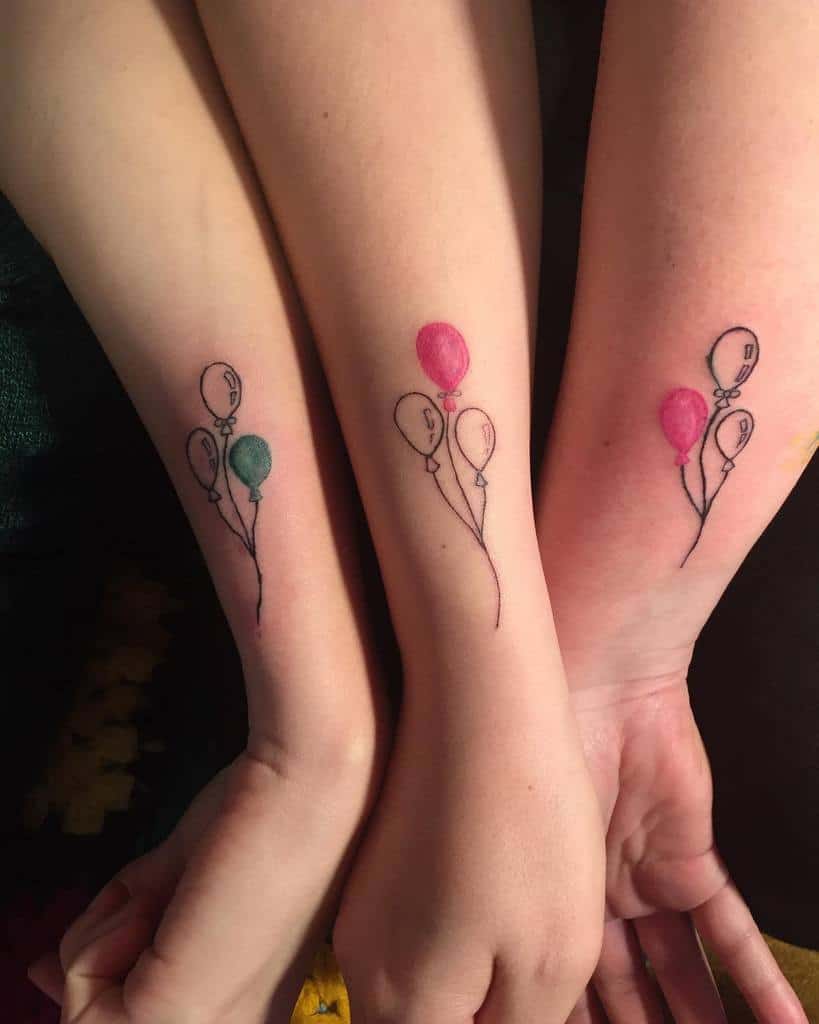 Matching sister tattoos featuring three balloons with one colored green differently from two pink balloons