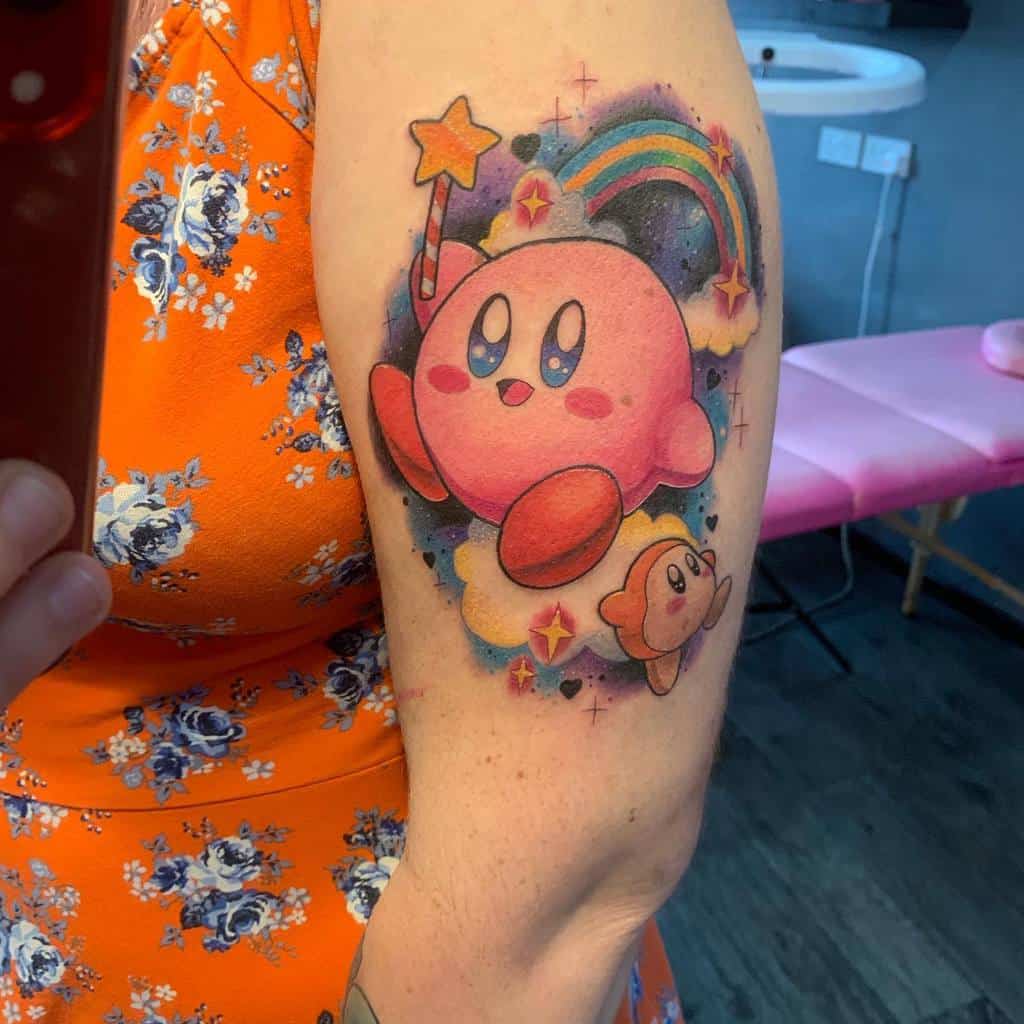 Kirby tattoo floating on a cloud with a star wand, a rainbow, and Waddle Dee, a colorful, dreamy design with sparkles and soft shading