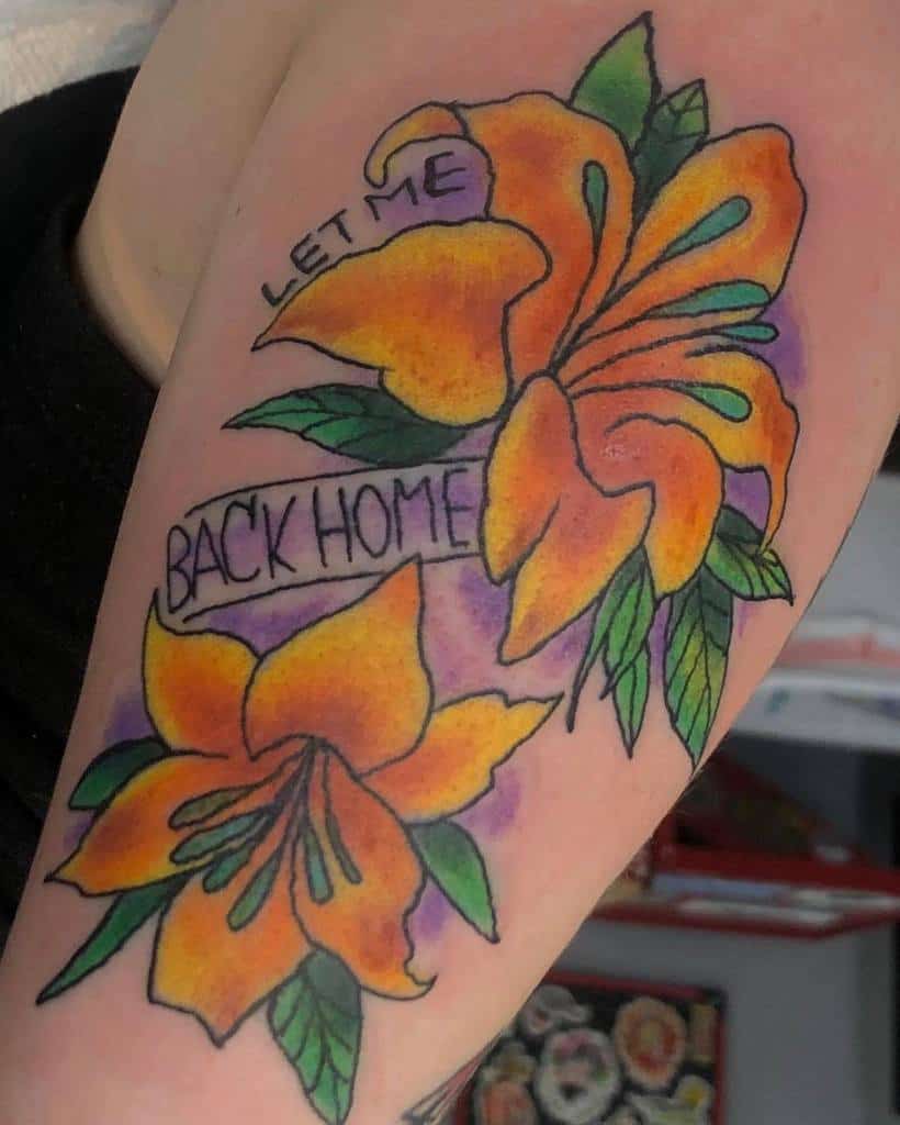 Bright tattoo of two orange lilies with green leaves and a banner reading 'Let me back home'