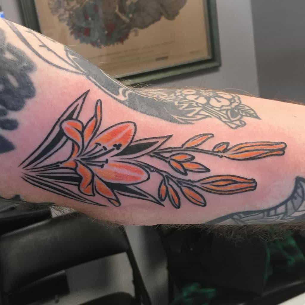 Bold traditional-style tattoo of an orange lily with black outlines and minimal shading, creating a striking floral design