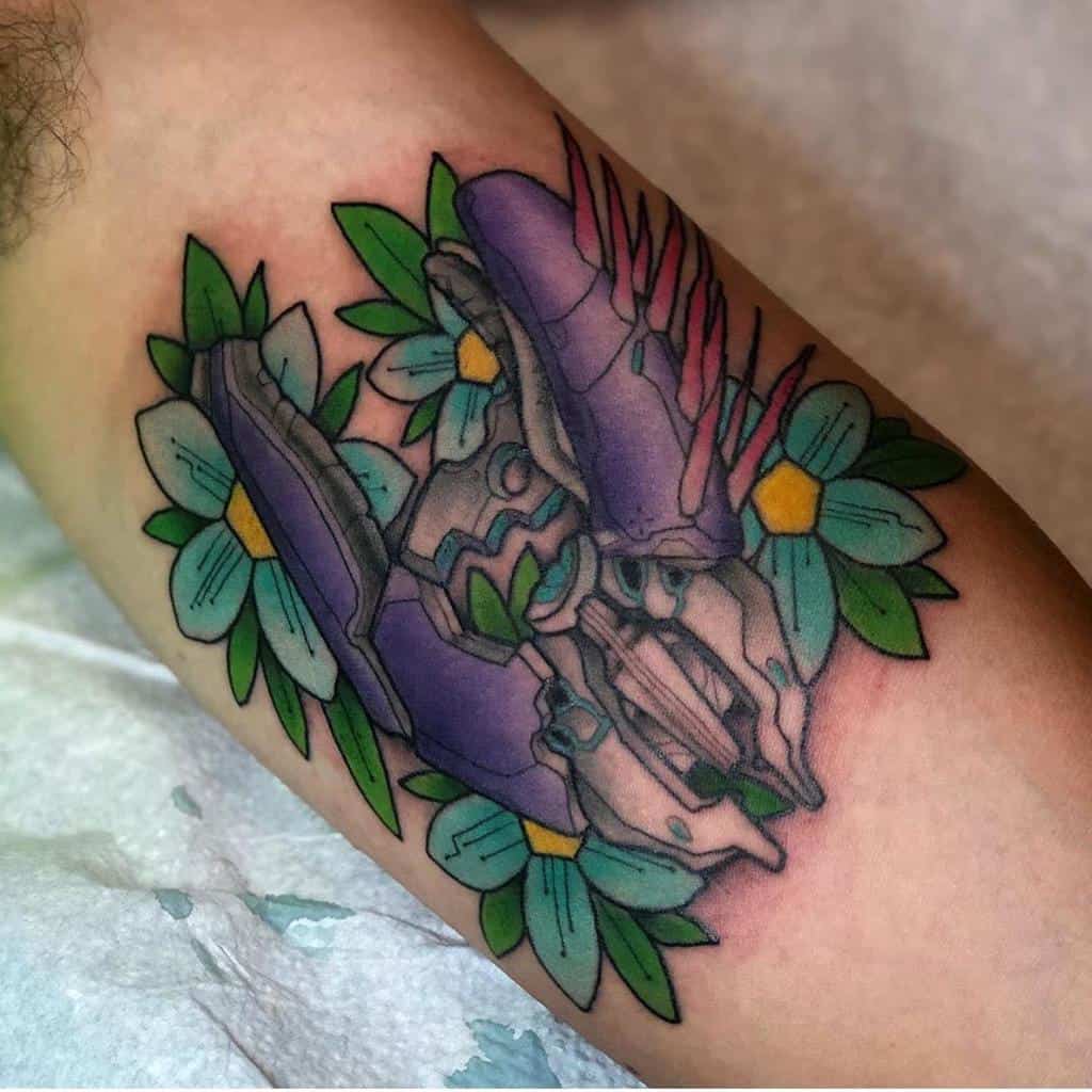 Vibrant Halo tattoo of the iconic Needler weapon, surrounded by delicate flowers and greenery, blending sci-fi with nature on the arm.