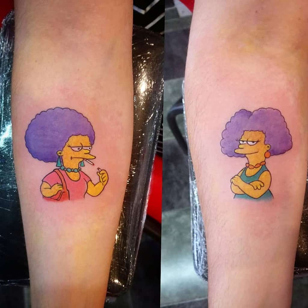 Matching sister tattoos featuring Simpsons style characters with purple afros, one smoking and the other with arms crossed