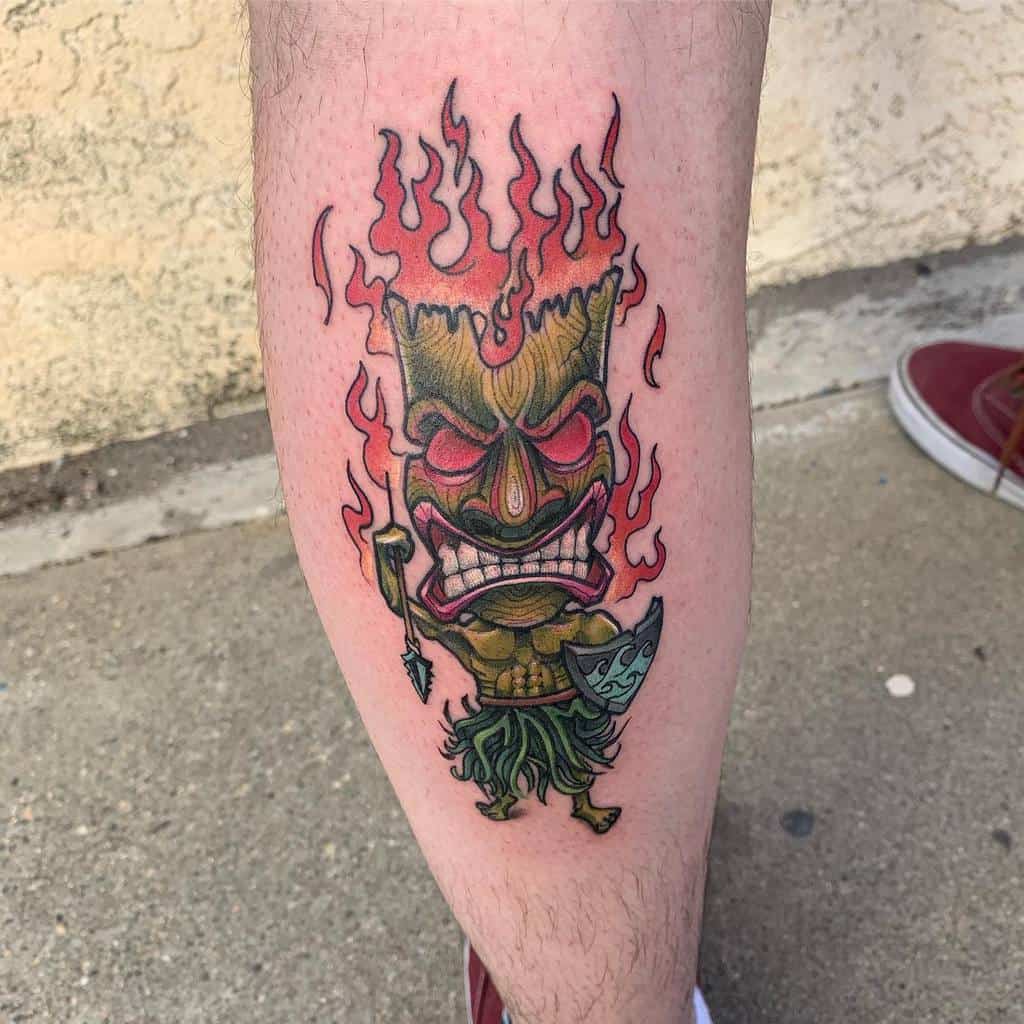 Vibrant Tiki tattoo featuring a fierce Tiki mask with flames rising from its top, holding a spear, with bold colors and intricate details