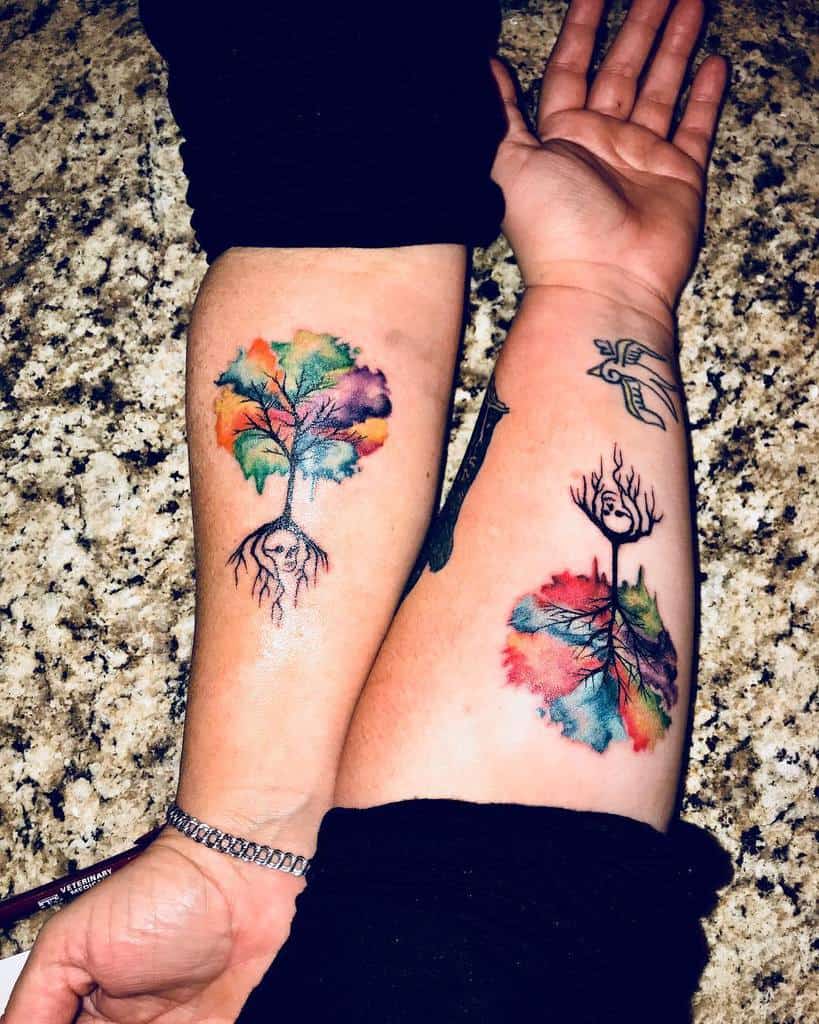 Vibrant matching mother-daughter tattoos featuring colorful trees with roots and skulls, blending watercolor elements 