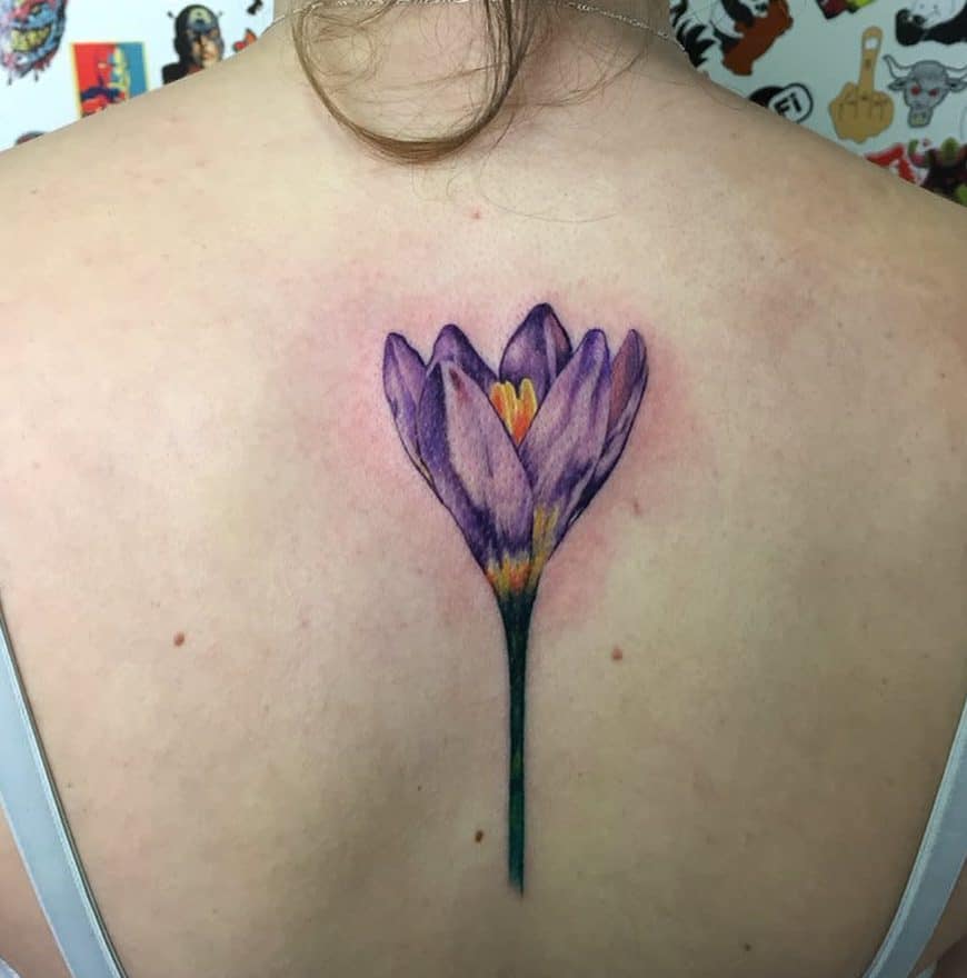 Delicate violet crocus tattoo, symbolizing renewal and hope, with realistic shading and vibrant yellow accents