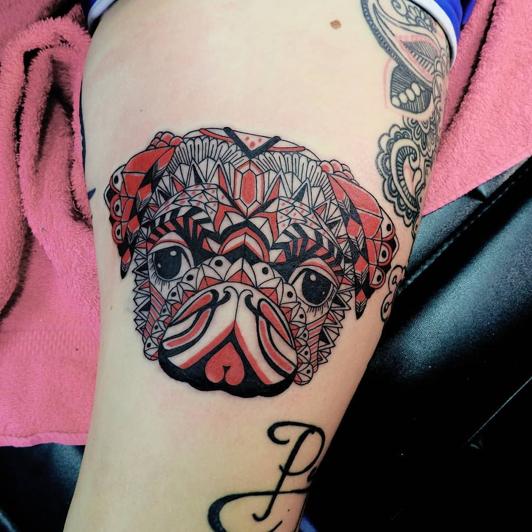 Colorful geometric pug tattoo, featuring intricate patterns and red, black, and white details