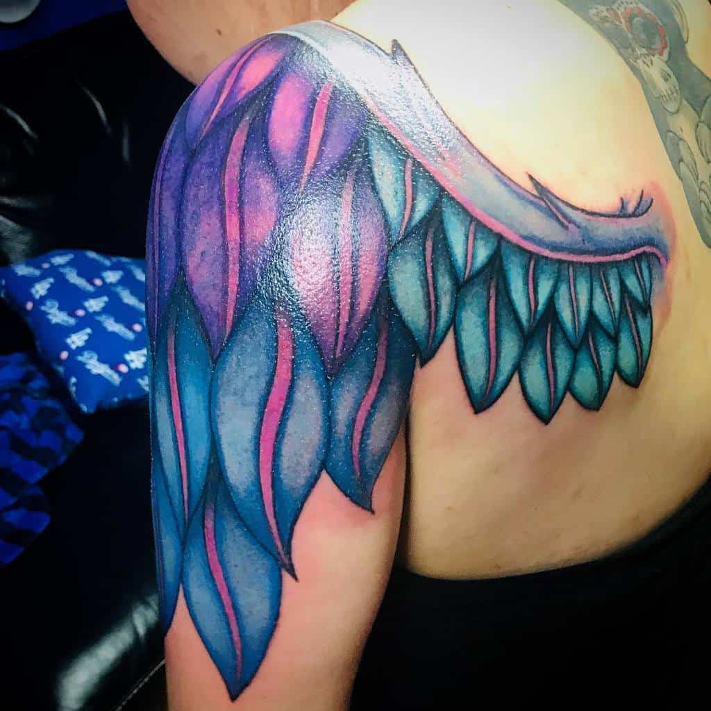 Vibrant wing tattoo featuring bold blue and purple feathers with a dynamic, artistic design