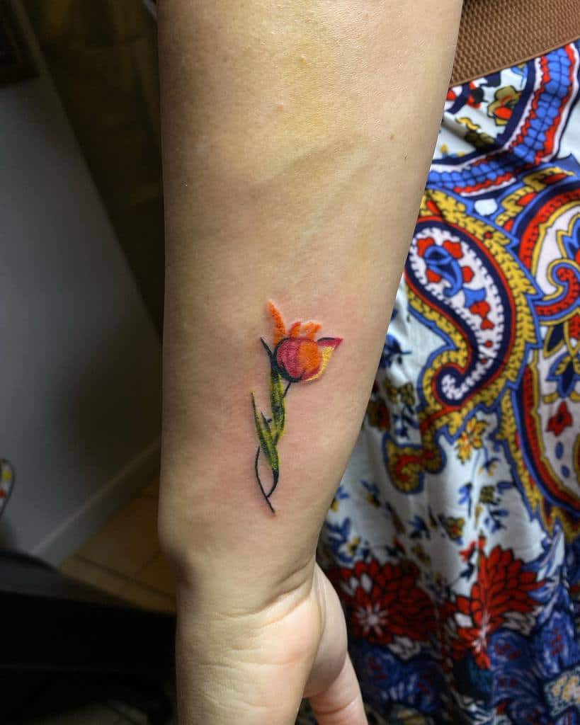 A small tulip tattoo on a forearm