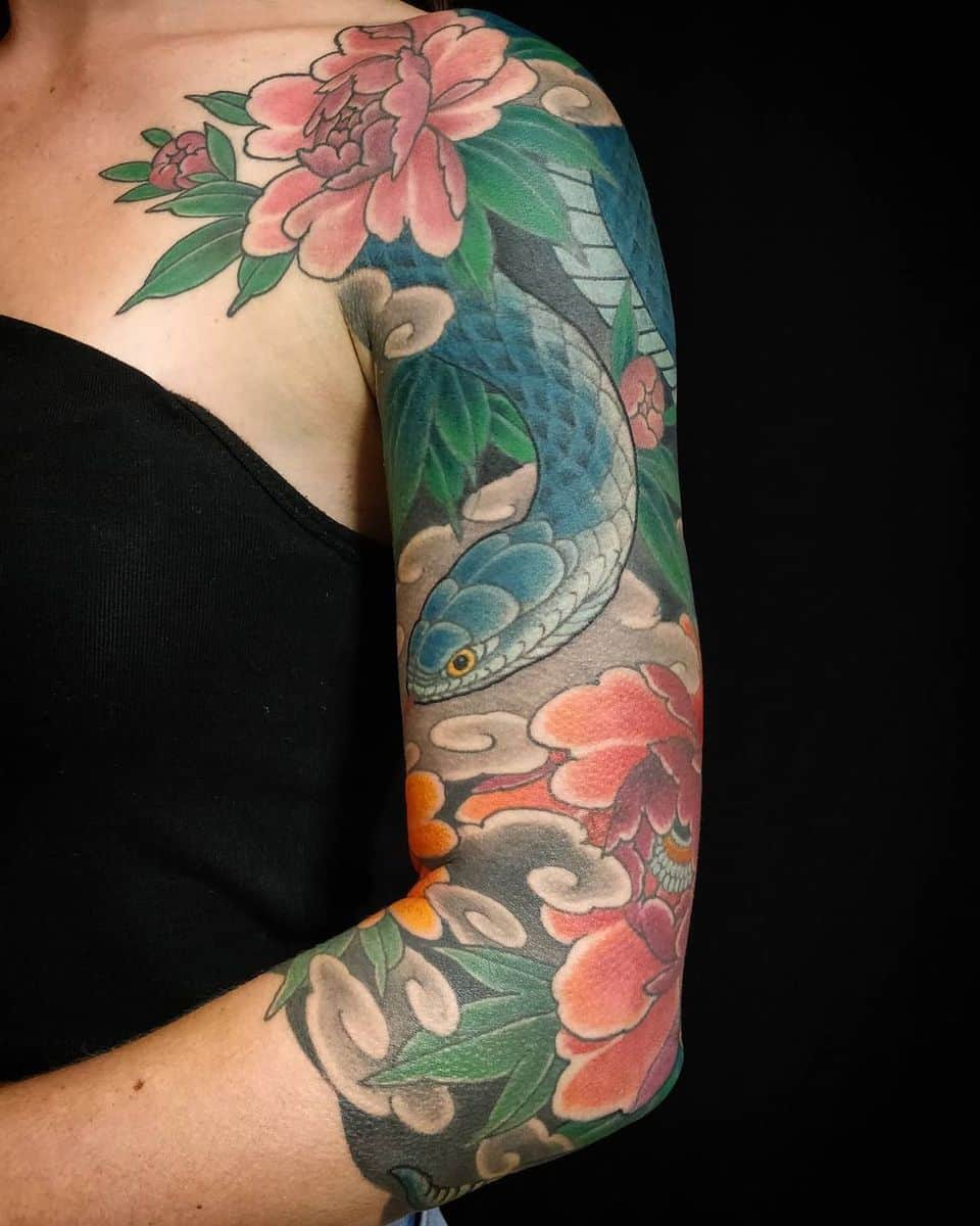 Arm tattoo featuring a blue snake entwined with pink and orange flowers