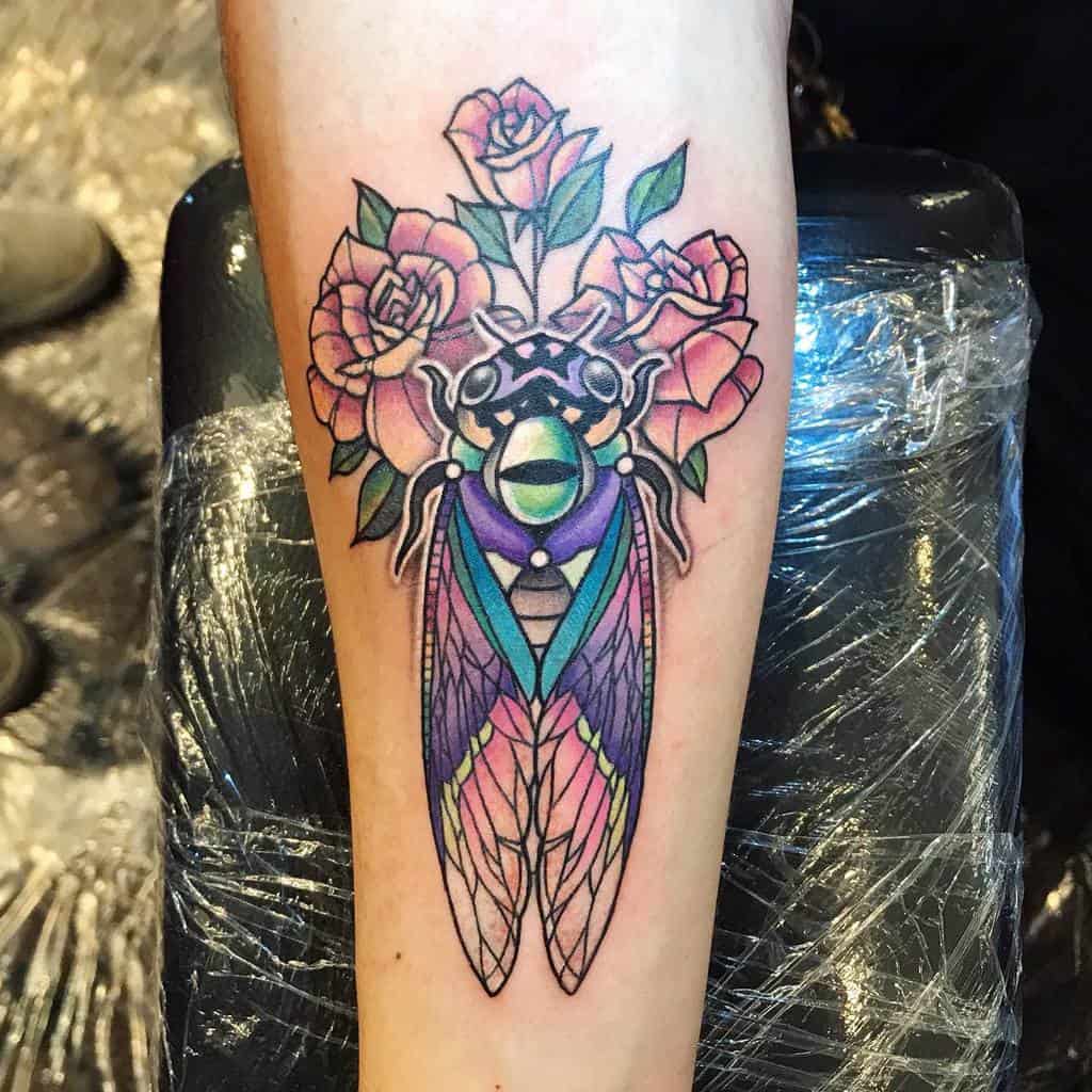 Colorful cicada tattoo with roses on a forearm