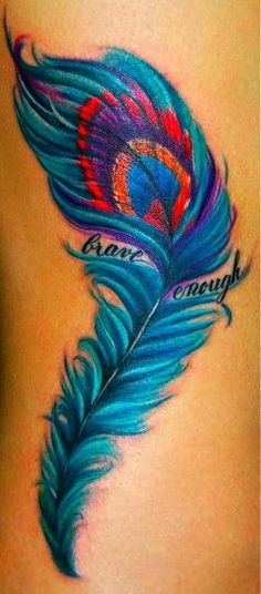 Vibrant peacock feather tattoo with rich blue, purple, and red hues, featuring the phrase 'brave enough' written across the design.