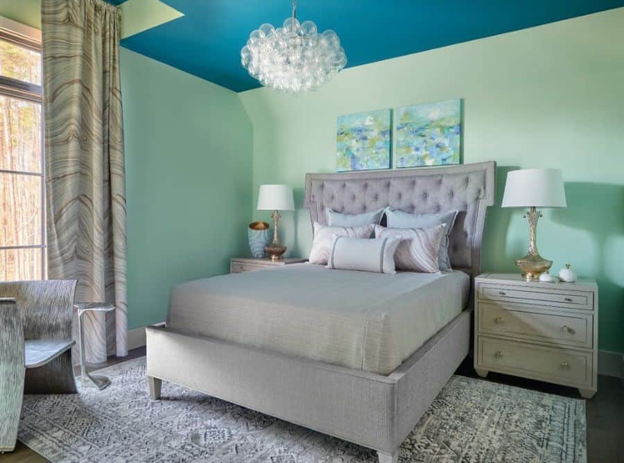 Stylish bedroom with a gray bed, green walls, blue ceiling, decorative chandelier, and two lamps on side tables