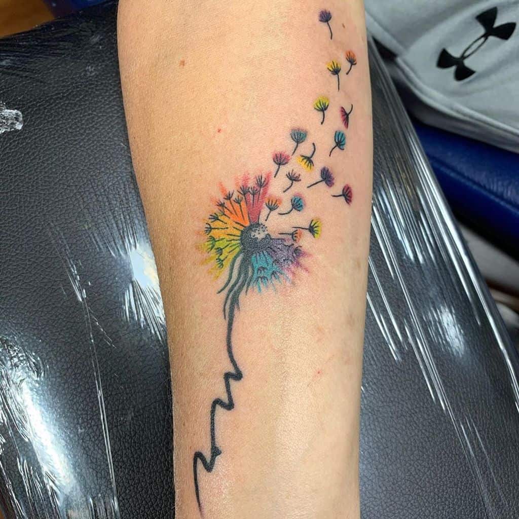 Vibrant dandelion tattoo with rainbow colors and scattered seeds, symbolizing diversity, freedom, and new beginnings.