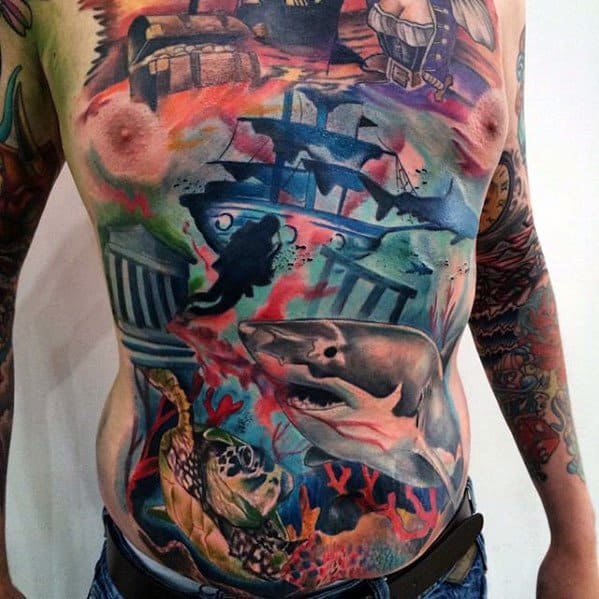 Vibrant full torso tattoo of an underwater shipwreck scene with sharks, sea turtle, ruins, treasure chest, coral, and marine life.