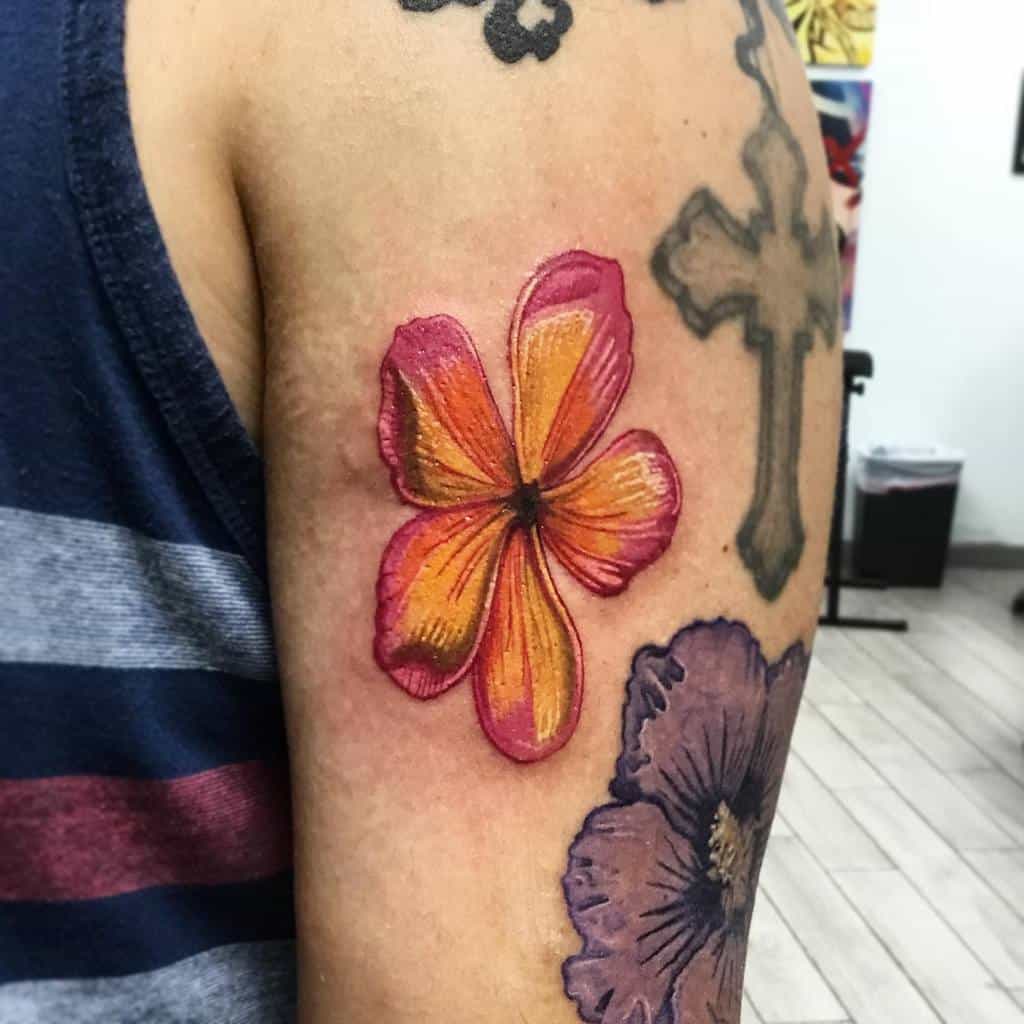 Upper arm tattoo featuring a vibrant orange and pink plumeria flower with detailed shading, standing out among other designs