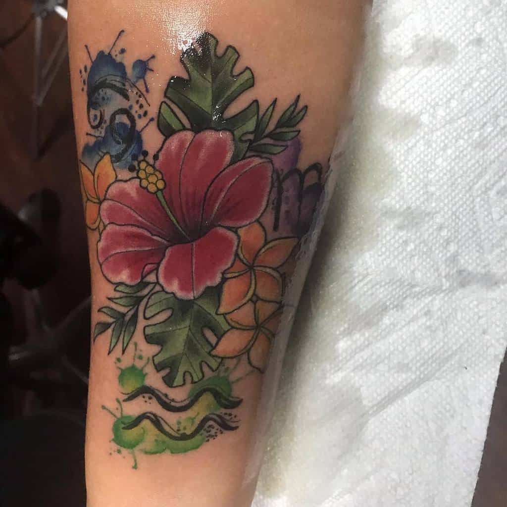 Forearm tattoo featuring a vibrant red hibiscus, orange plumeria flowers, tropical leaves, and abstract splashes of blue and green ink