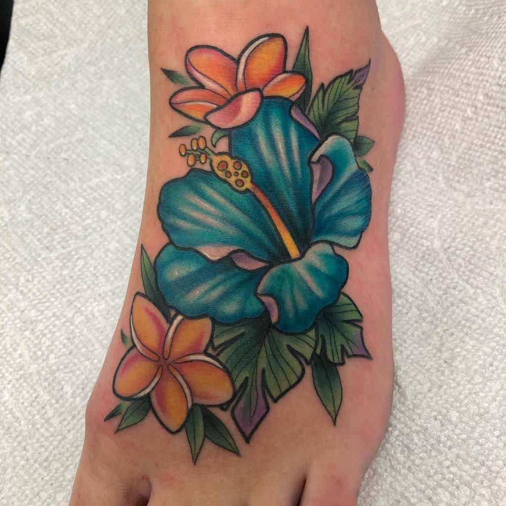 Vibrant foot tattoo featuring a large blue hibiscus flower accompanied by smaller orange and yellow plumeria flowers with green leaves