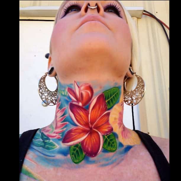 A bold and vibrant neck tattoo featuring a stunning Hawaiian flower design in rich reds, oranges, and greens, with intricate shading and a tropical backdrop