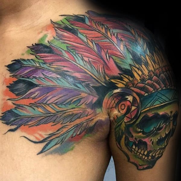 Colorful tattoo on shoulder of skull wearing Native American headdress with vibrant feathers