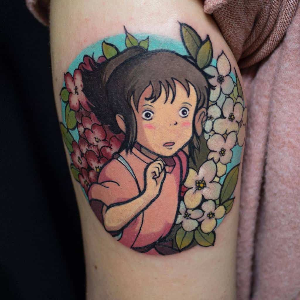 Colorful tattoo of Chihiro from Spirited Away, surrounded by vibrant flowers, with a circular blue background design