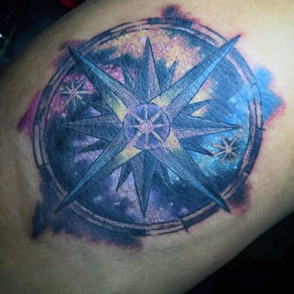 Tattoo of a detailed compass rose with a colorful, starry background