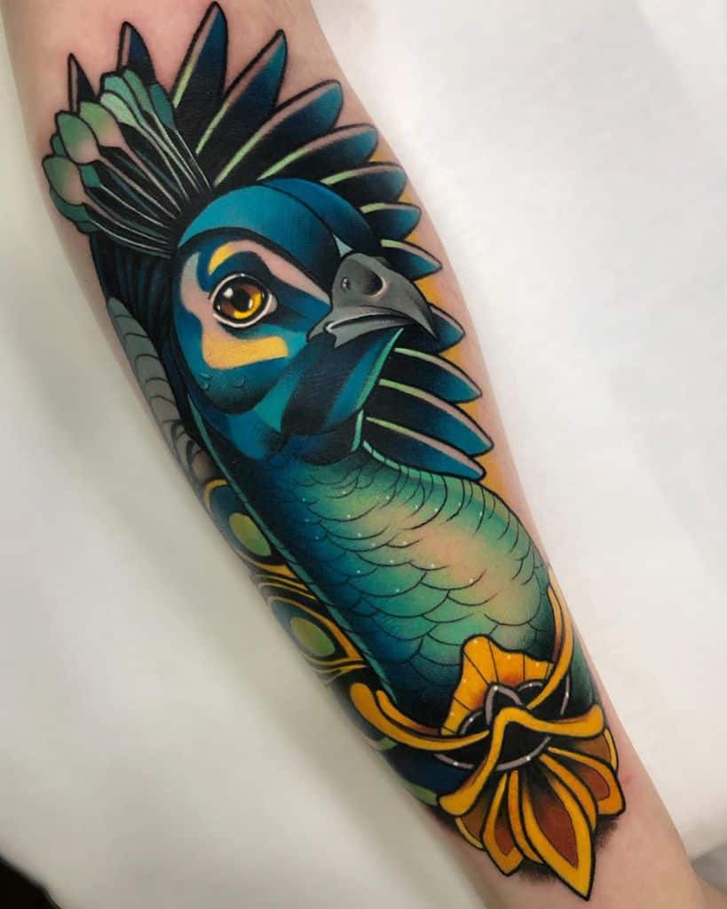Colorful peacock tattoo on forearm with detailed feathers and a decorative orange flower