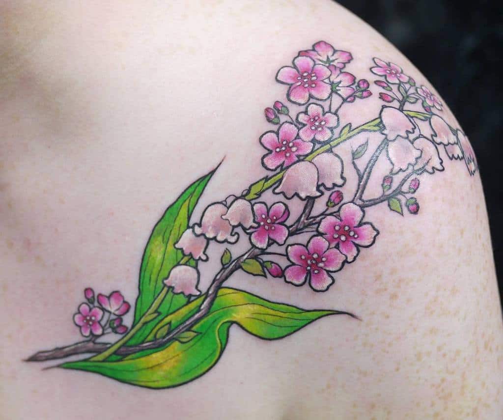 Elegant floral tattoo, featuring intertwined Lily of the Valley and cherry blossoms with delicate pink petals and vibrant green leaves