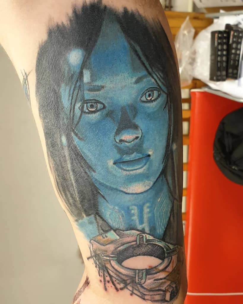 Realistic tattoo of Cortana from Halo, glowing in vibrant blue with detailed shading, inked on the upper arm for a sci-fi-inspired design.