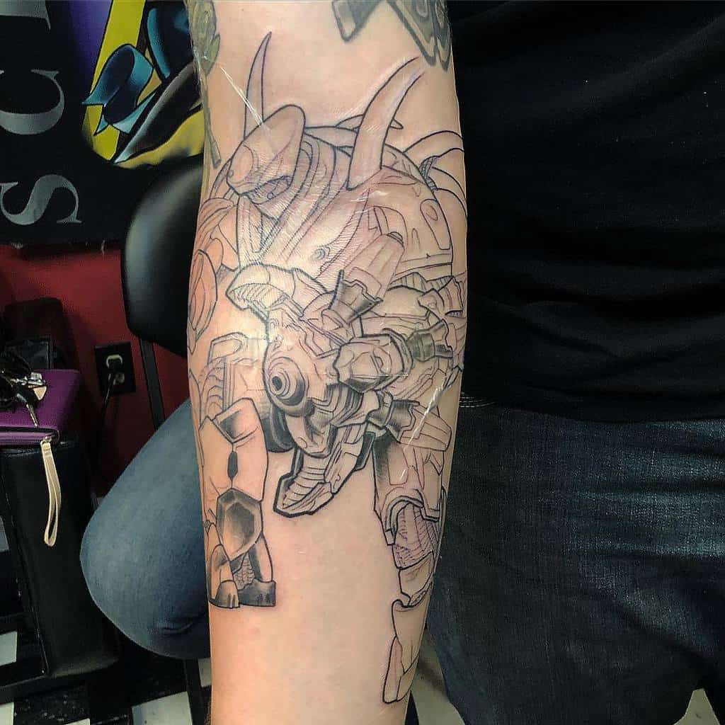 Intricate black and gray tattoo of a Halo Hunter (Lekgolo) in battle stance, inked on the forearm with fine linework and shading.
