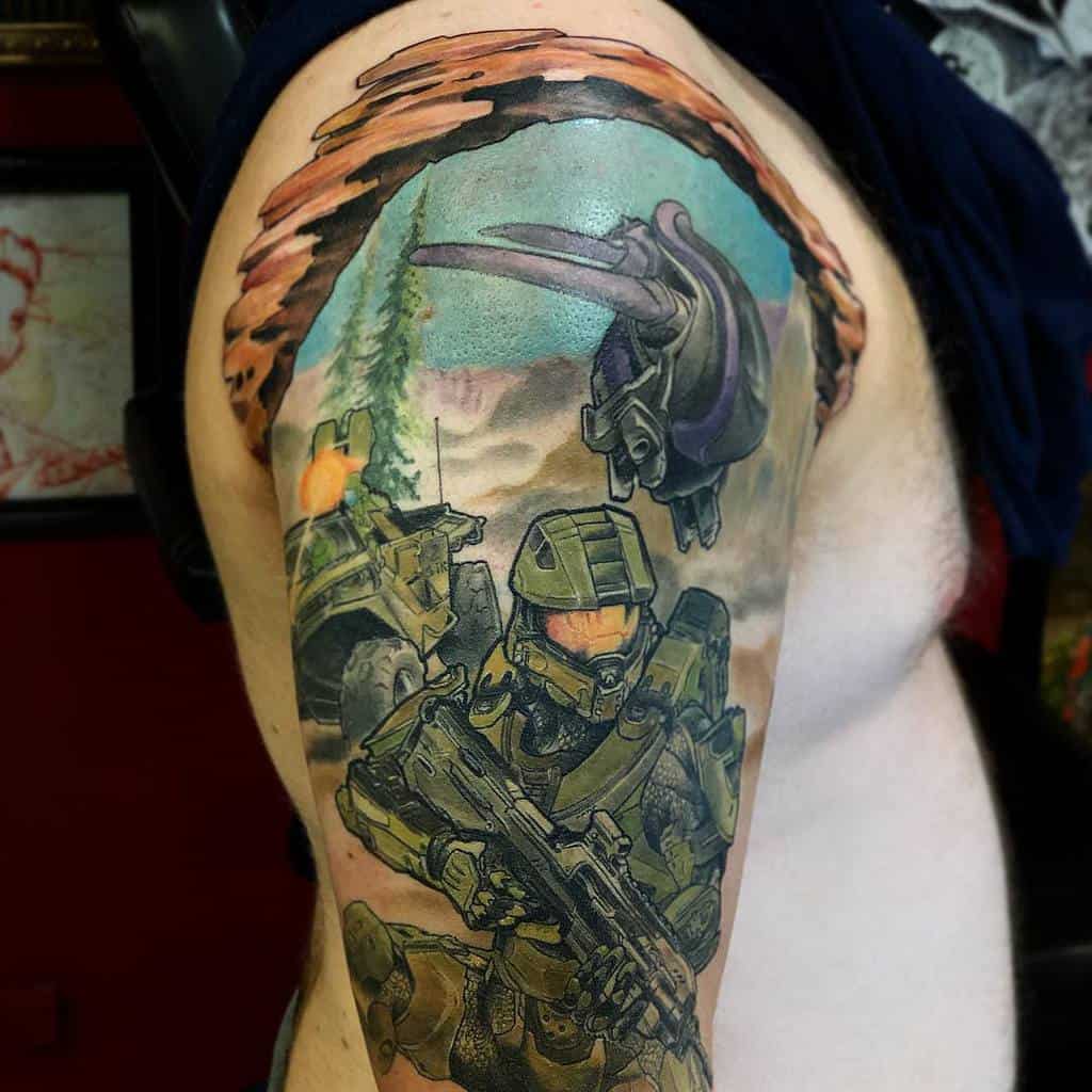 Vibrant Halo tattoo featuring Master Chief in battle, a Warthog, and a Banshee overhead, framed by a torn-skin effect on the upper arm.