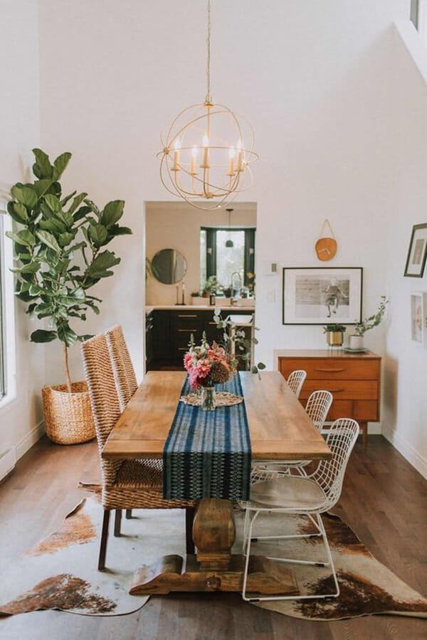 Boho-style dining room with wooden table, decorative plants, and modern chandelier.