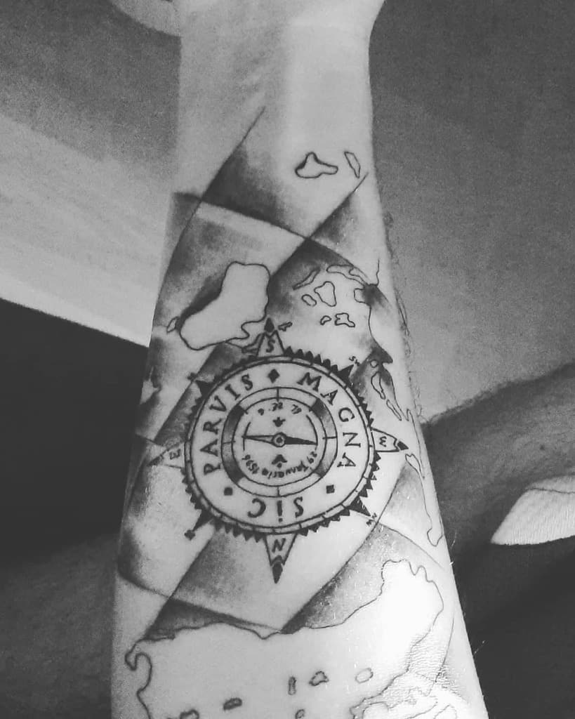 Black and white tattoo of a compass with text "Sic Parvis Magna" on a forearm