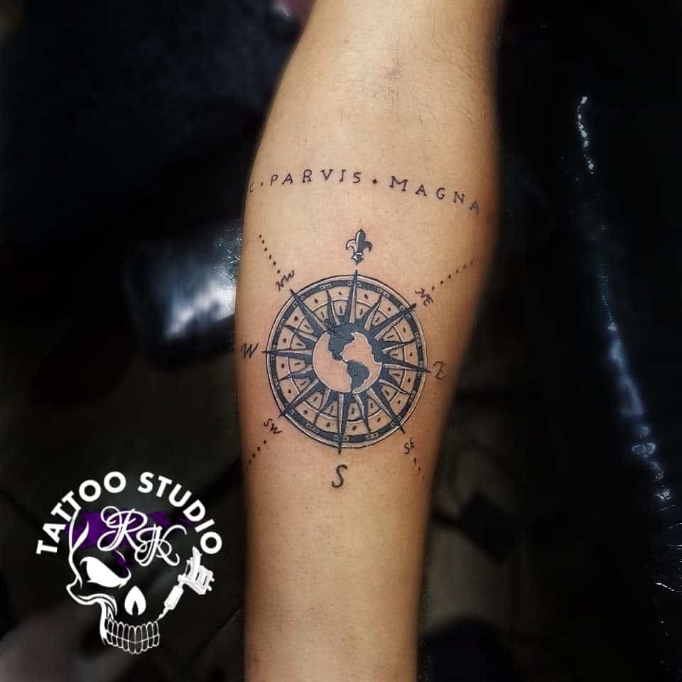 Circular compass tattoo with "Sic Parvis Magna" text above it on forearm