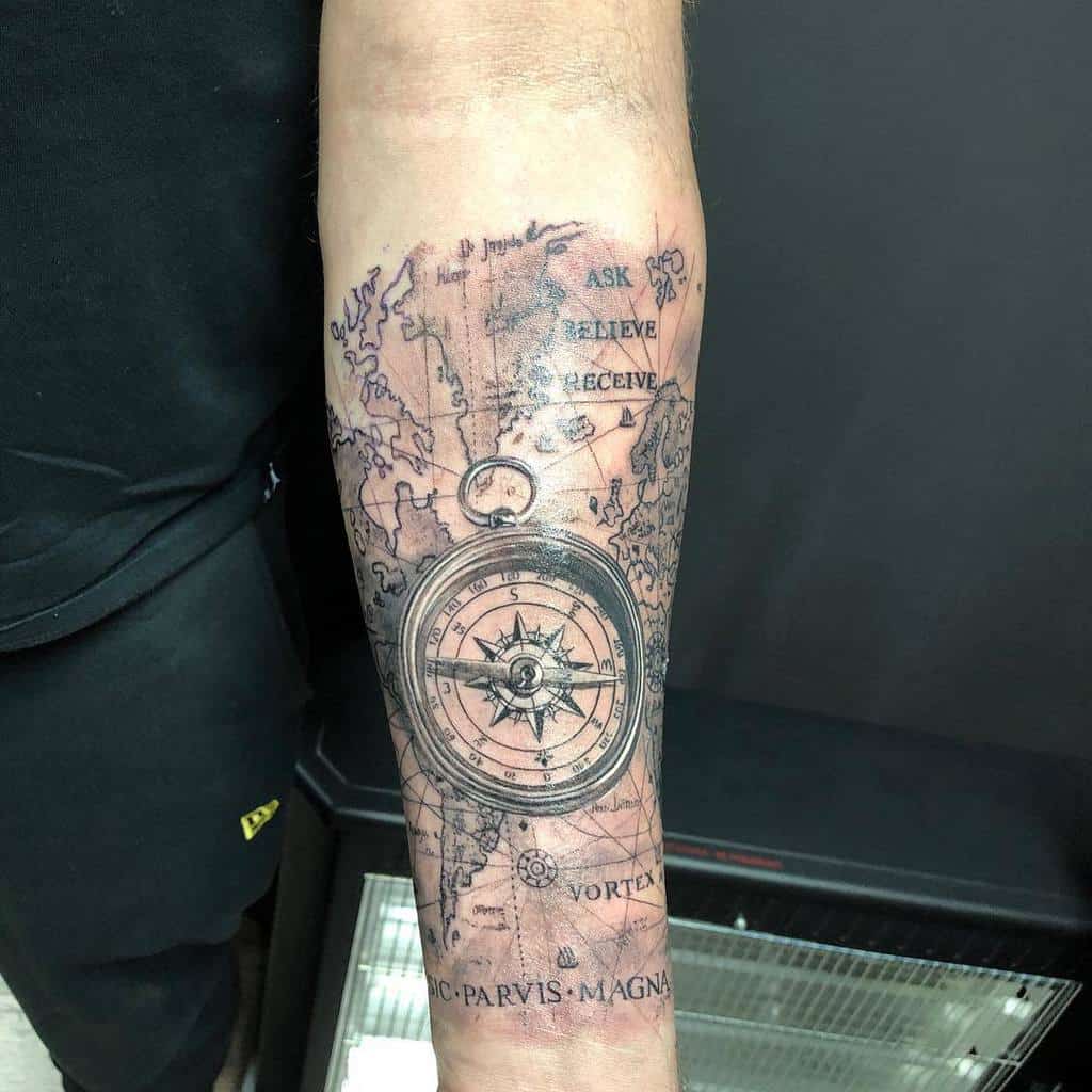 Forearm tattoo of a compass over a world map with text 'Ask Believe Receive' and 'Sic Parvis Magna' at the bottom