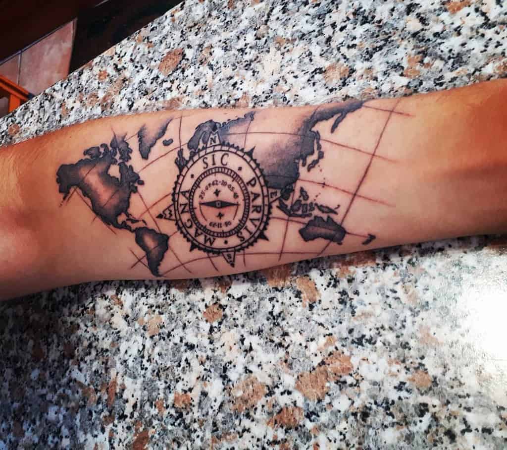 Forearm tattoo featuring a compass labeled 'Sic Parvis Magna' over a detailed shaded world map design