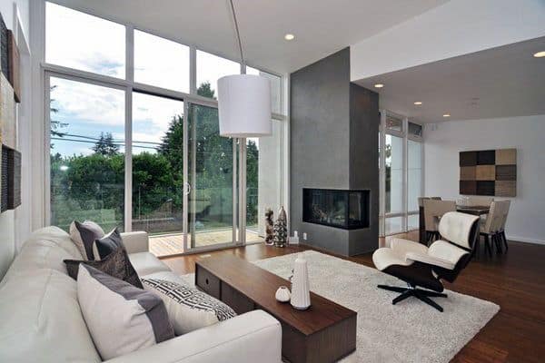 Contemporary living room with concrete corner fireplace, white sofa, and modern armchair.