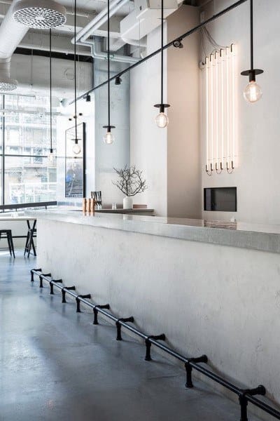 Modern bar featuring a sleek concrete top, complemented by industrial lighting and minimalist decor.