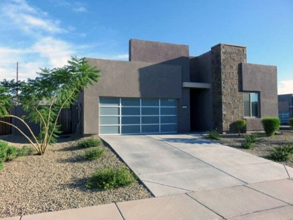Simple concrete driveway with clean lines leading to a modern glass-paneled garage door.