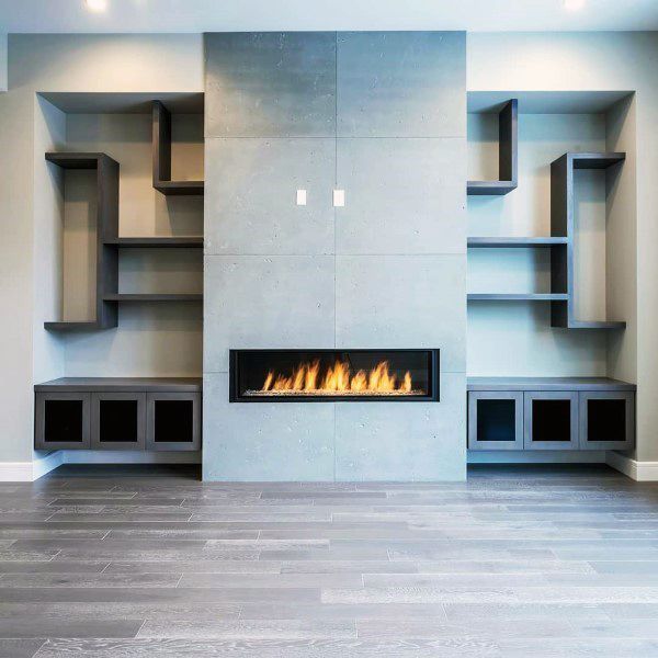 Modern concrete fireplace with built-in shelving and sleek black cabinets on gray flooring.