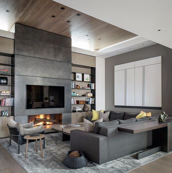 Contemporary living room with a black concrete fireplace, wood-paneled ceiling, and built-in shelving.