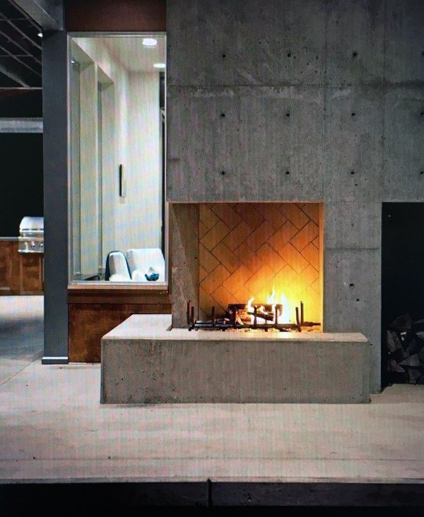Minimalist concrete fireplace with herringbone brick interior and sleek modern design.