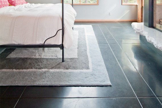 Minimalist bedroom with a white bed, black metal frame, gray rug, and glossy concrete floor
